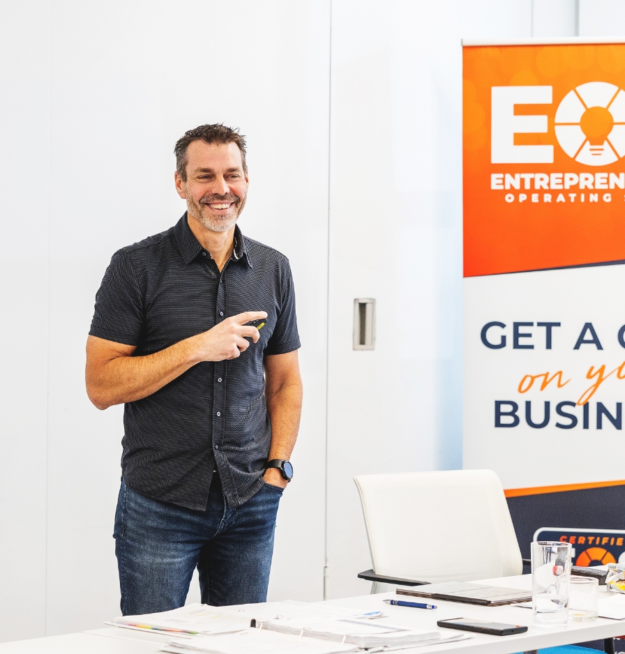 Jon Weening smiling standing next to EOS signage