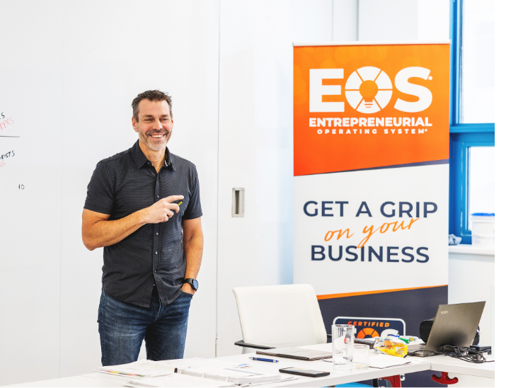 Jon Weening smiling standing next to EOS signage